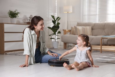 Mother and her daughter with robotic vacuum cleaner at home