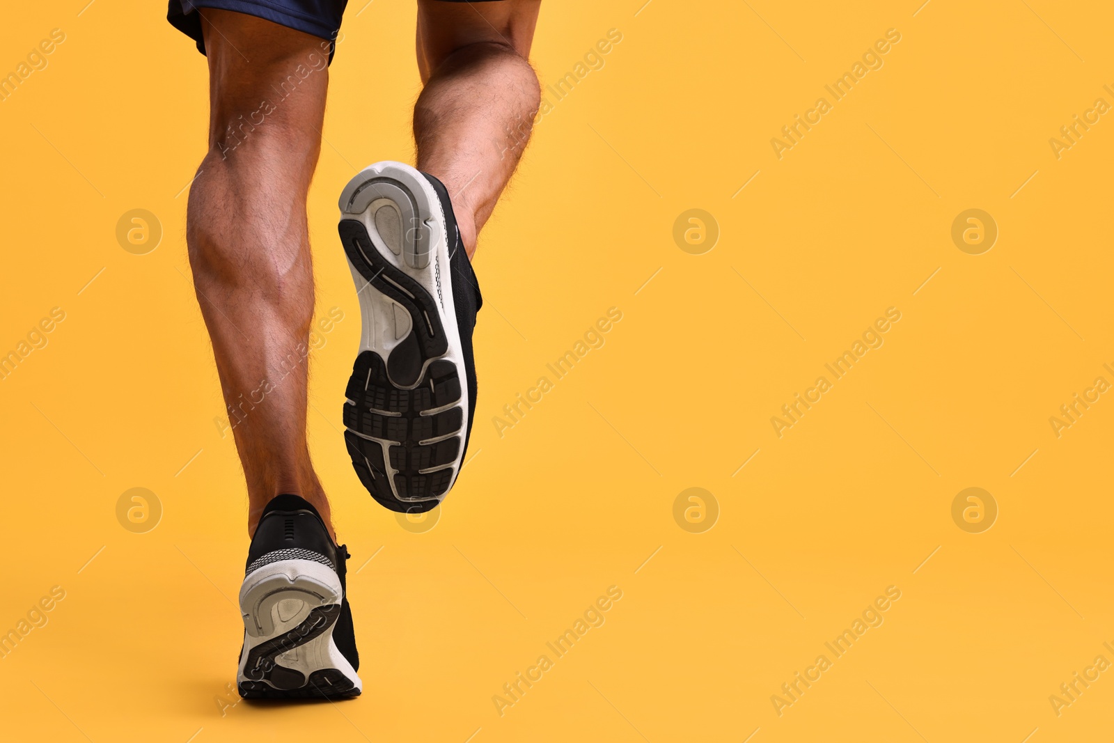 Photo of Man running on orange background, closeup. Space for text