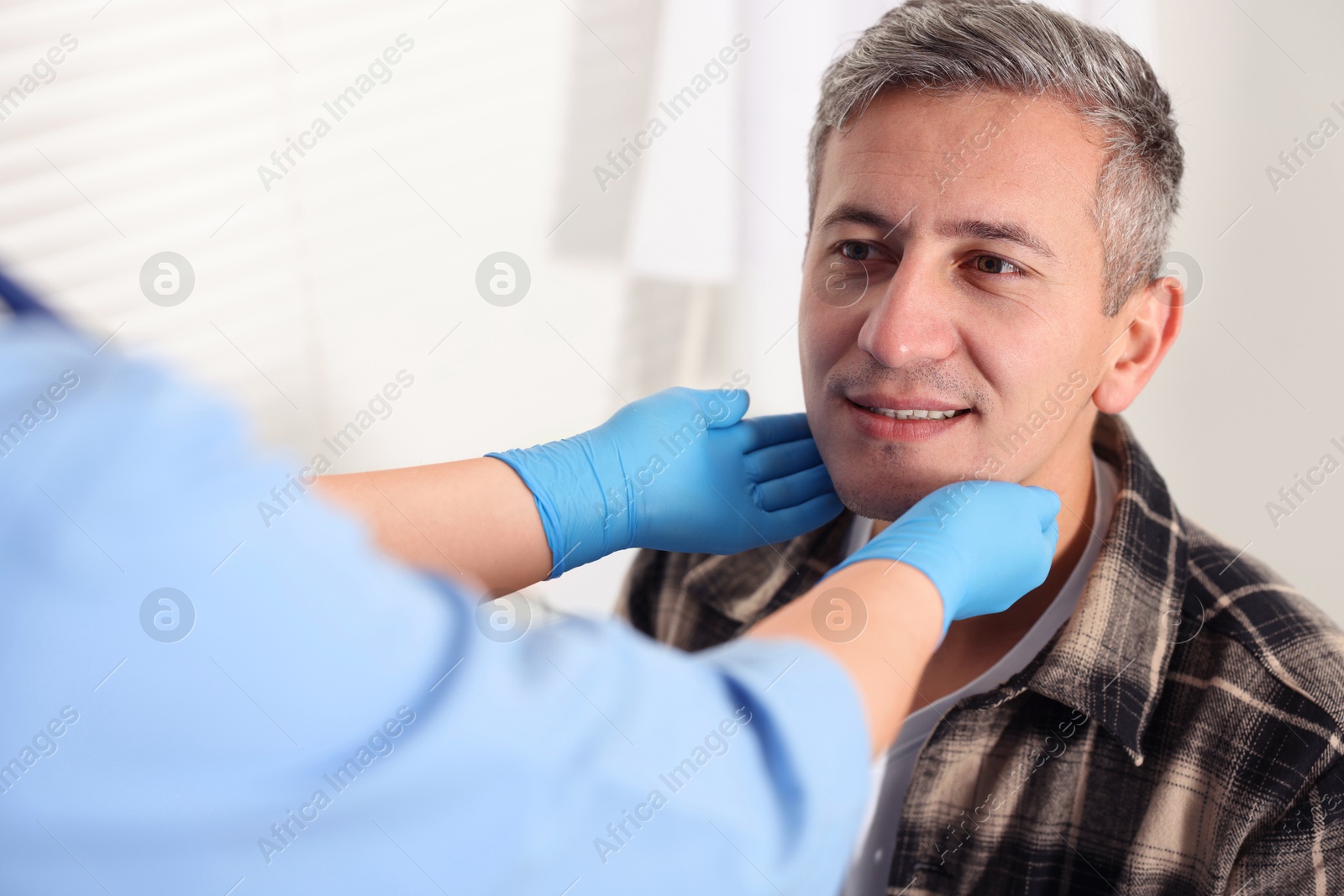 Photo of Doctor examining man's throat in clinic during appointment