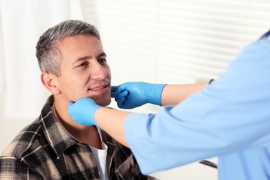 Doctor examining man's throat in clinic during appointment