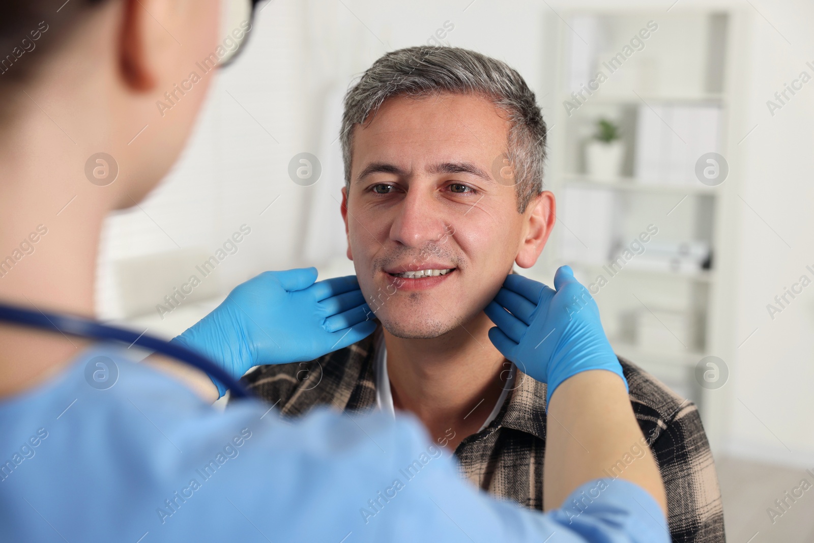 Photo of Doctor examining man's throat in clinic during appointment