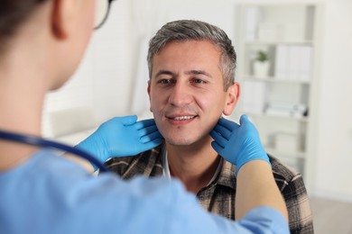 Doctor examining man's throat in clinic during appointment