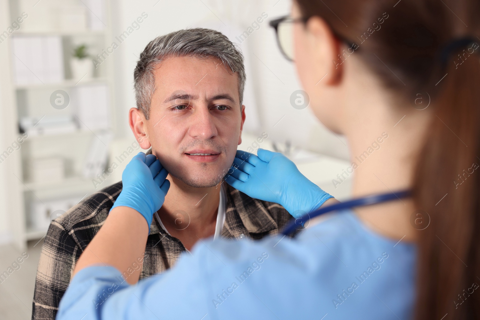 Photo of Doctor examining man's throat in clinic during appointment