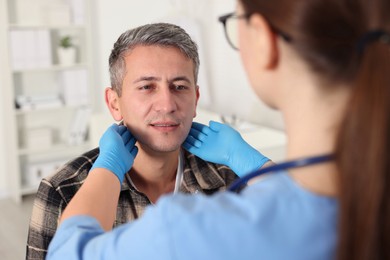 Photo of Doctor examining man's throat in clinic during appointment