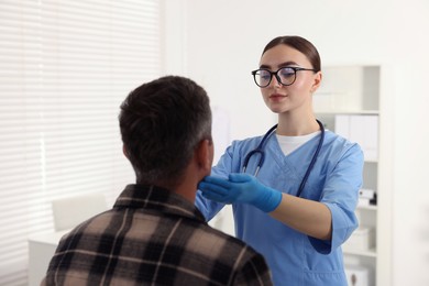 Doctor examining man's throat in clinic during appointment