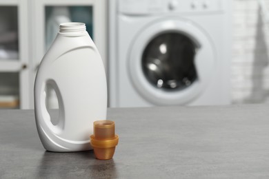 Photo of Laundry detergent and cap on grey table, space for text