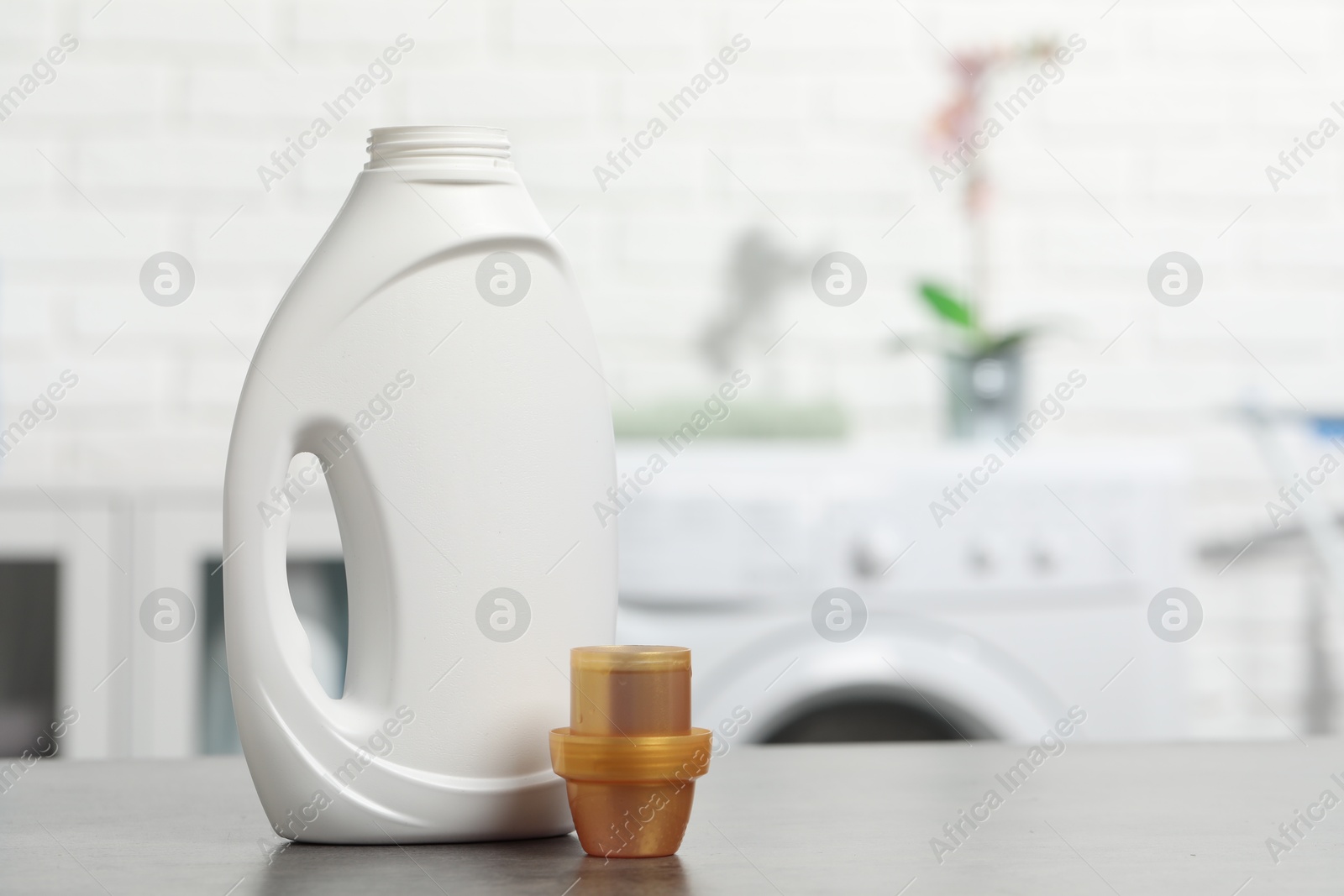 Photo of Laundry detergent and cap on grey table, space for text