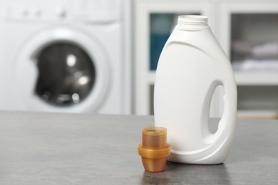 Photo of Laundry detergent and cap on grey table, space for text