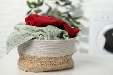 Photo of Basket full of laundry on white table in bathroom. Space for text