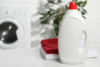 Photo of Detergent and basket with towels on white table in bathroom, space for text