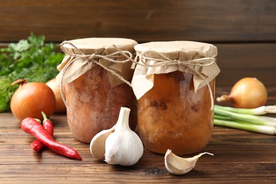 Photo of Canned meat in glass jars and fresh products on wooden table