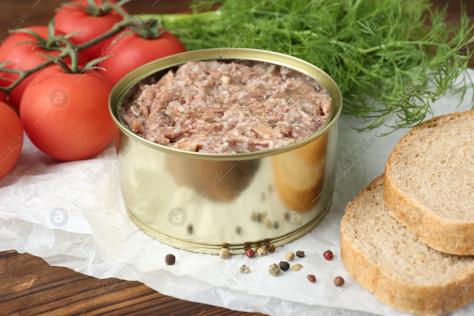 Photo of Canned meat in tin can served on wooden table, closeup