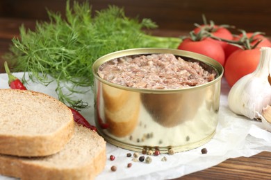 Photo of Canned meat in tin can served on wooden table, closeup