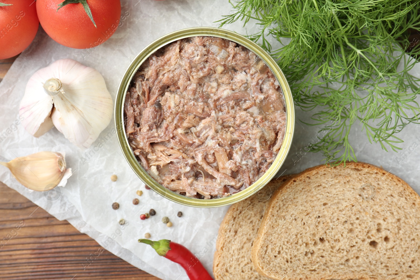 Photo of Canned meat in tin can served on wooden table, flat lay