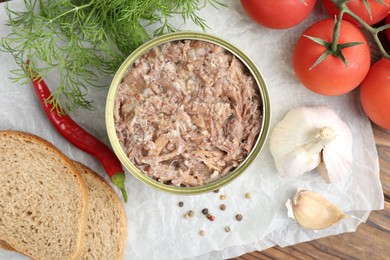 Canned meat in tin can served on wooden table, flat lay