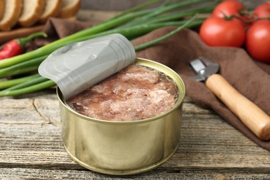 Canned meat in tin can on wooden table, closeup