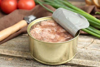 Canned meat in tin can on wooden table, closeup