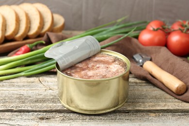 Photo of Canned meat in tin can on wooden table, closeup