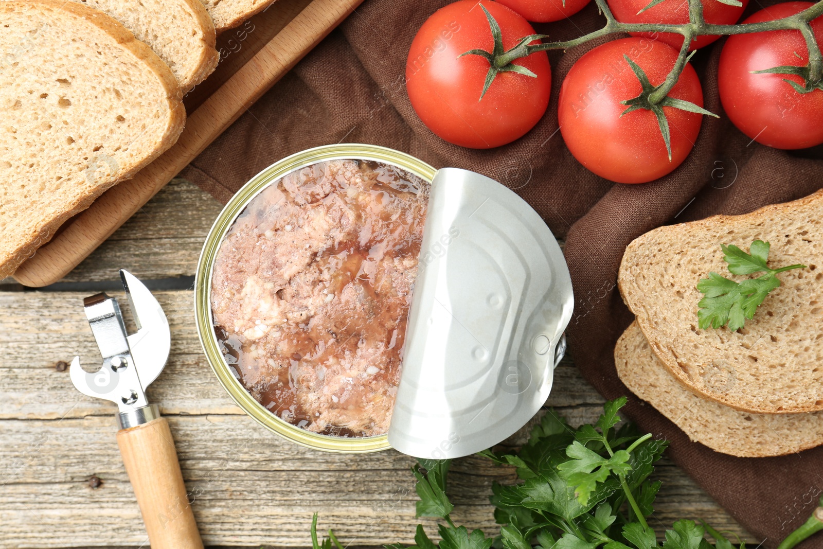 Photo of Canned meat in tin can served on wooden table, flat lay