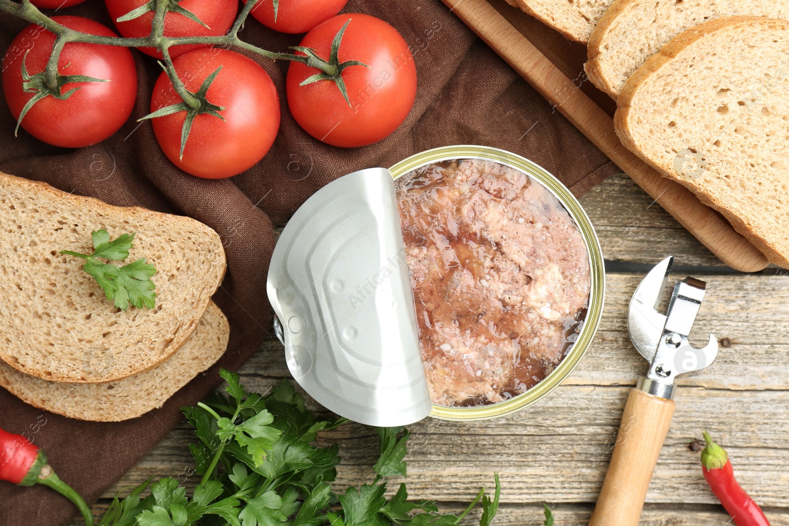 Photo of Canned meat in tin can served on wooden table, flat lay