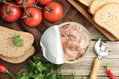 Canned meat in tin can served on wooden table, flat lay