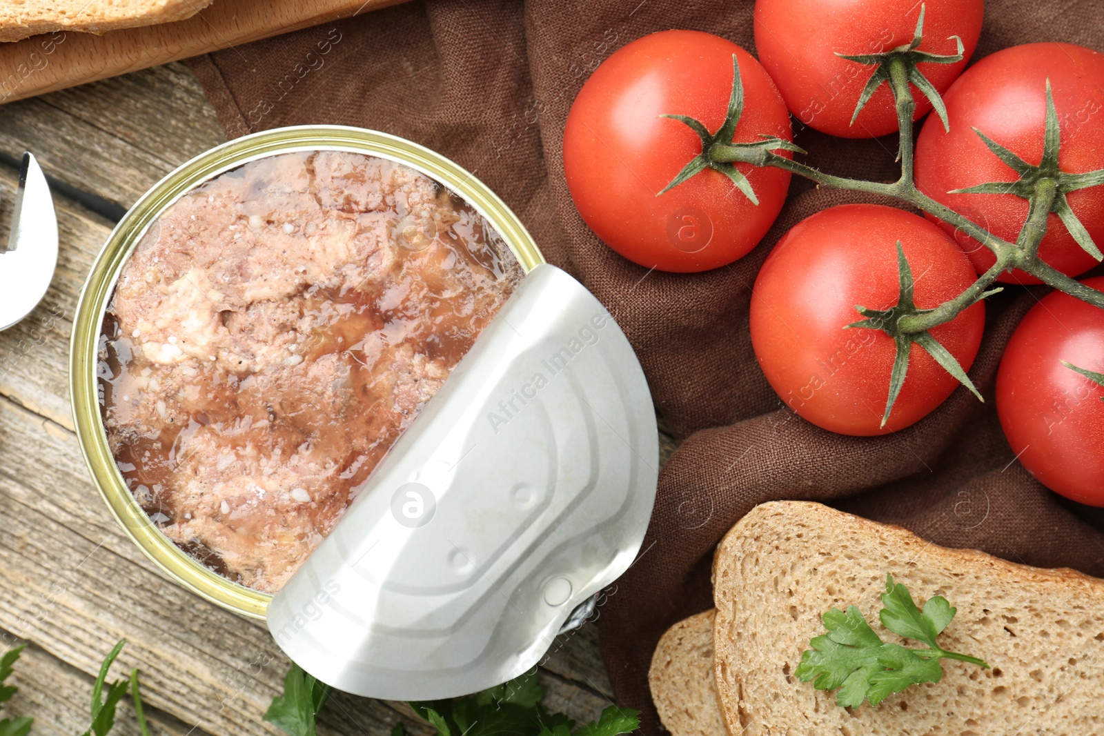 Photo of Canned meat in tin can served on wooden table, flat lay