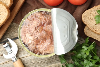 Canned meat in tin can served on wooden table, flat lay