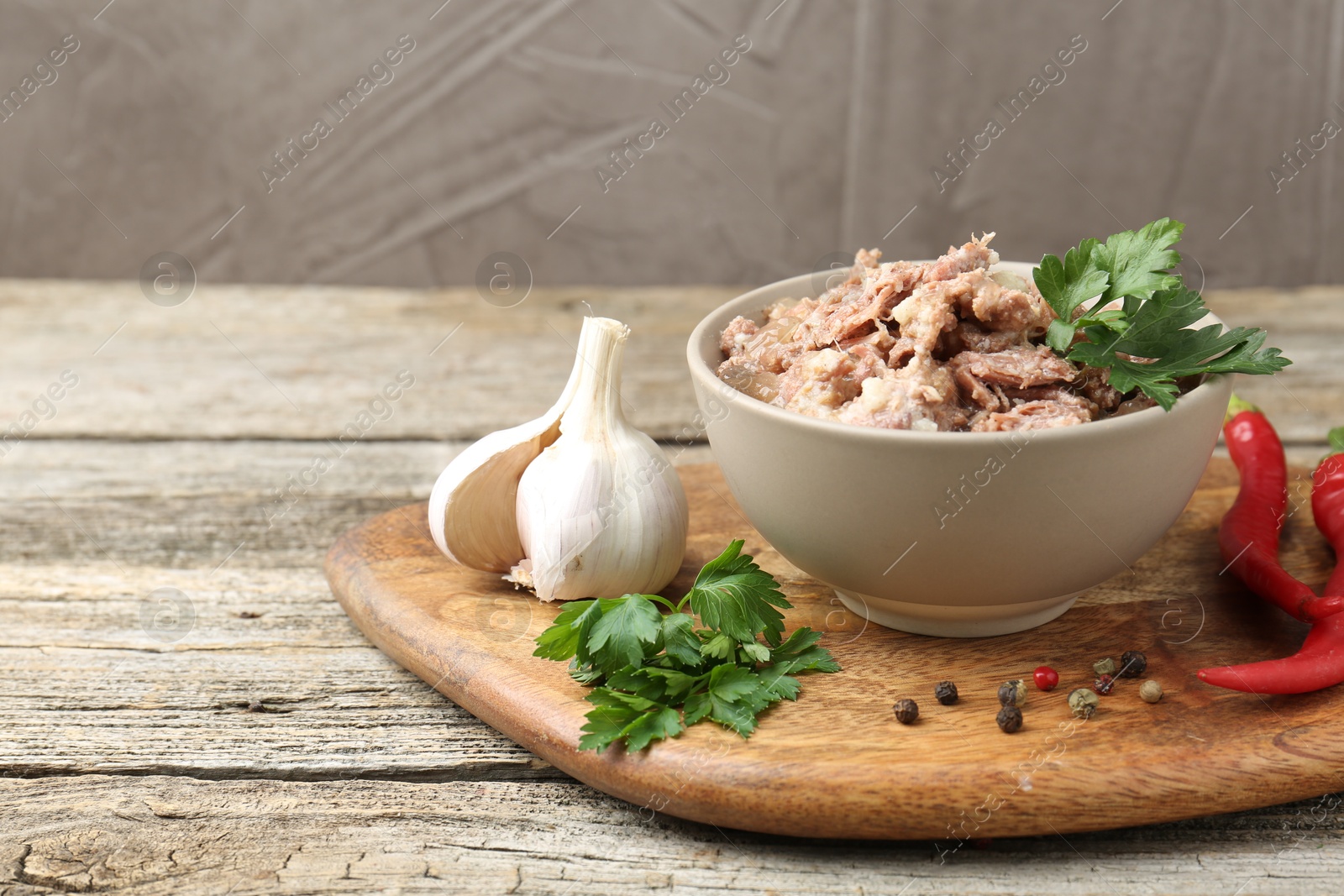 Photo of Canned meat in bowl and fresh products on wooden table, closeup. Space for text