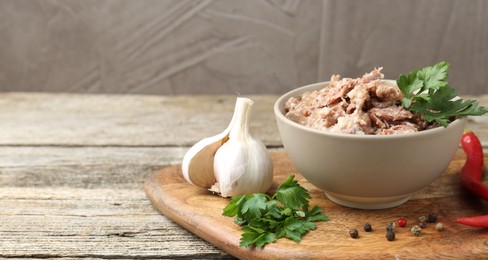 Photo of Canned meat in bowl and fresh products on wooden table, closeup. Space for text