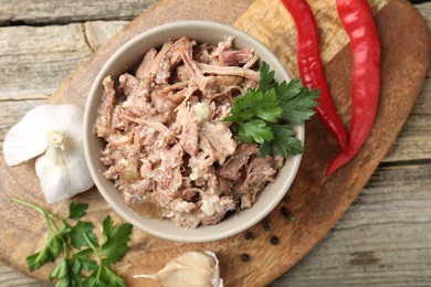 Photo of Canned meat in bowl and fresh products on wooden table, flat lay