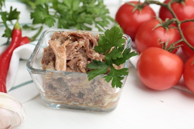 Photo of Canned meat with parsley in bowl on white table, closeup