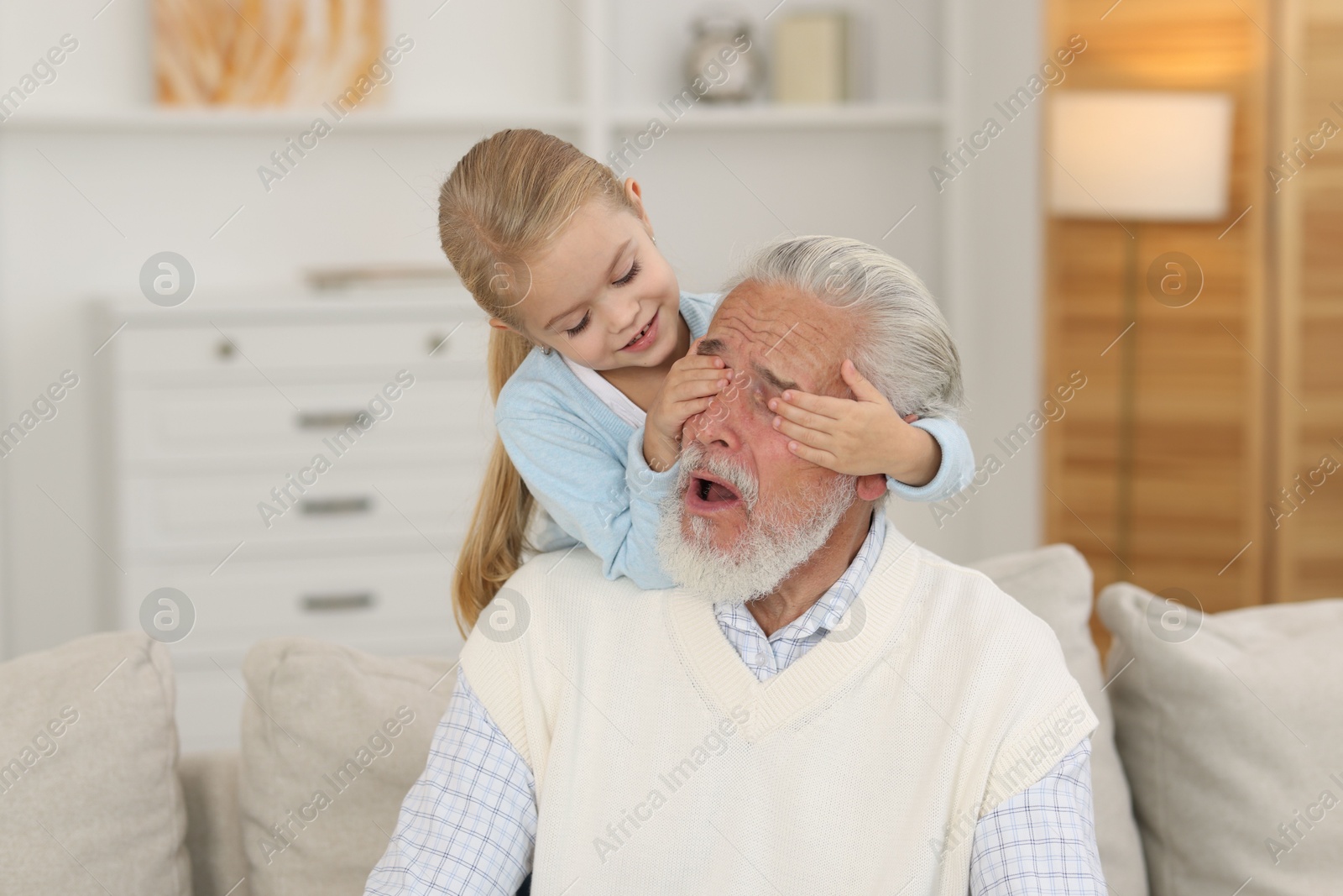 Photo of Grandpa and his granddaughter having fun at home