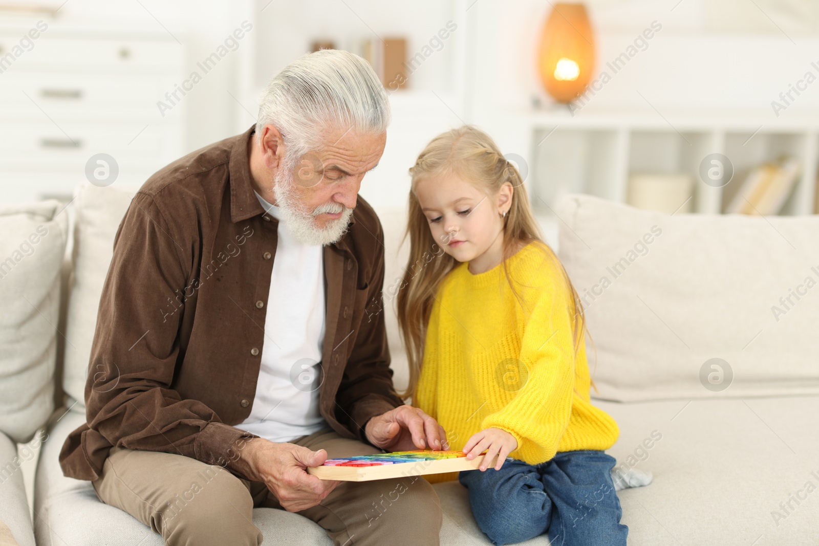 Photo of Grandpa and his granddaughter playing with math game Times table tray at home