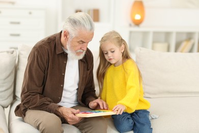 Grandpa and his granddaughter playing with math game Times table tray at home