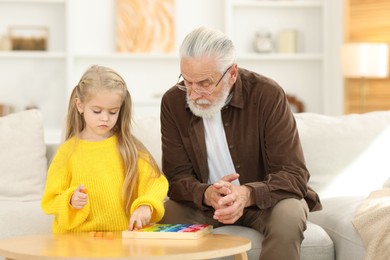 Photo of Grandpa and his granddaughter playing with math game Times table tray at home