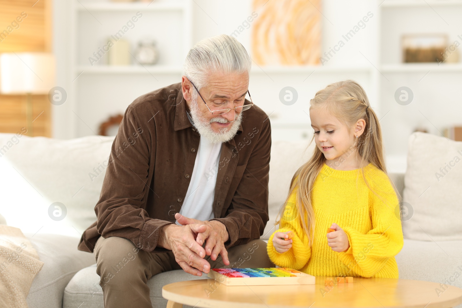 Photo of Grandpa and his granddaughter playing with math game Times table tray at home