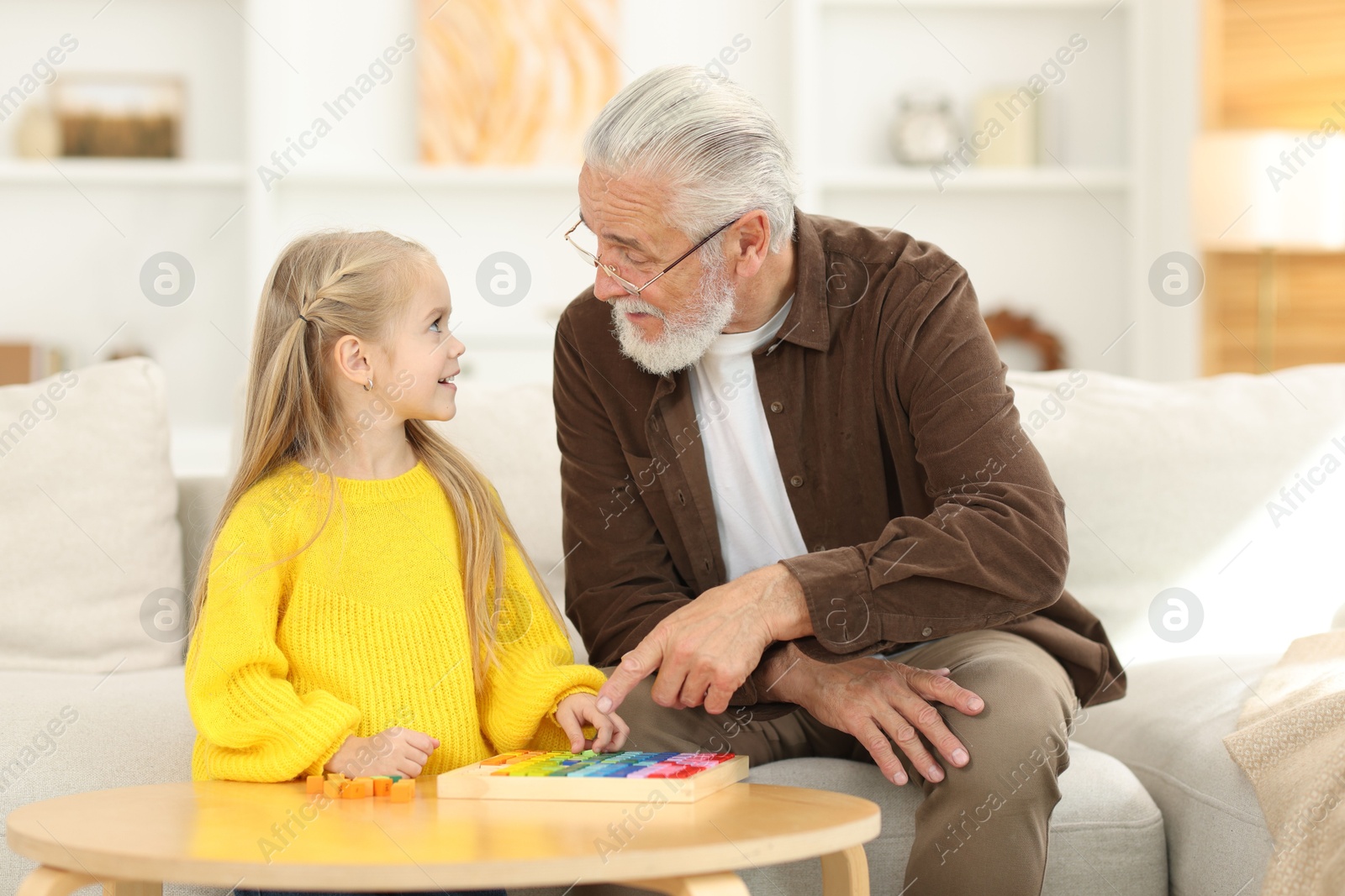 Photo of Grandpa and his granddaughter playing with math game Times table tray at home