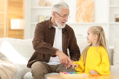 Grandpa and his granddaughter playing with math game Times table tray at home