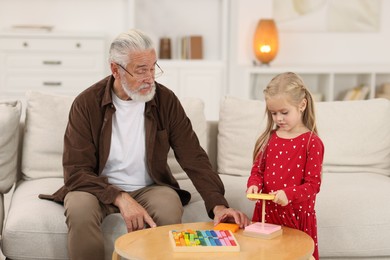 Photo of Grandpa and his granddaughter playing with toy pyramid at home