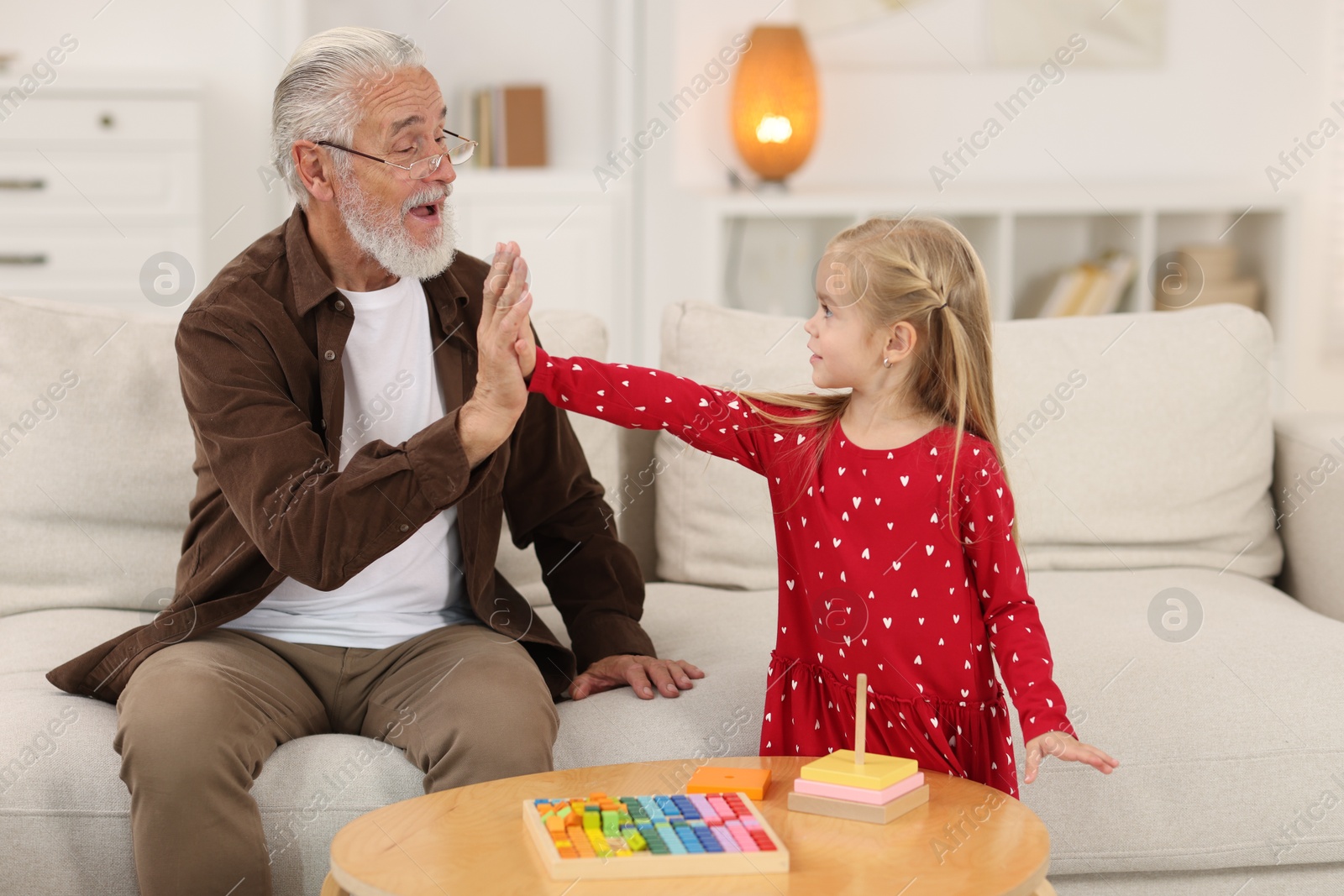 Photo of Grandpa and his granddaughter giving five at home