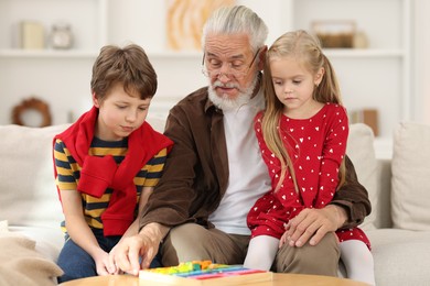 Grandpa and his grandkids playing with math game Times table tray at home