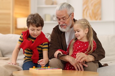 Grandpa and his grandkids playing with math game Times table tray at home