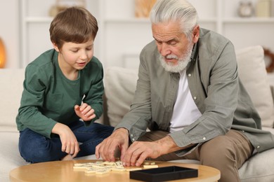 Photo of Grandpa and his grandson playing dominoes at table indoors