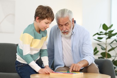 Grandpa and his grandson playing with math game Times table tray at home