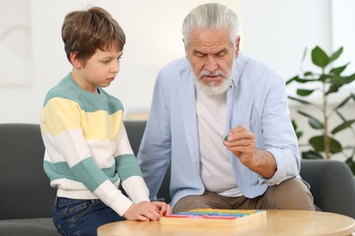 Photo of Grandpa and his grandson playing with math game Times table tray at home