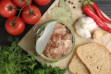 Canned meat in tin can and other products on wooden table, top view