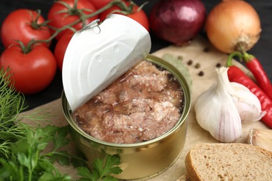 Canned meat in tin can and other products on table, closeup