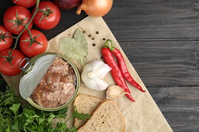 Canned meat in tin can and other products on wooden table, top view. Space for text