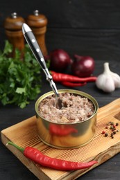 Photo of Canned meat in tin can and spices on wooden table