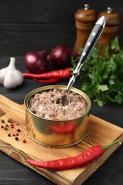 Canned meat in tin can and spices on wooden table